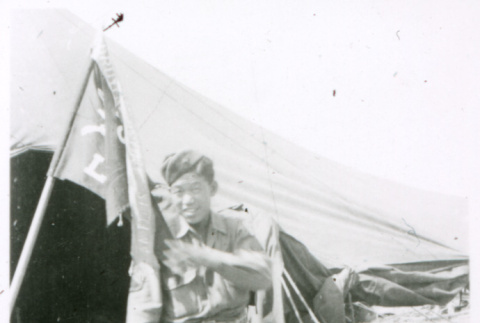 Soldier with flag in front of tent (ddr-densho-1007-833)