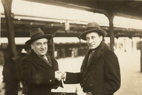 Two men shaking hands in a train station (ddr-njpa-1-2028)