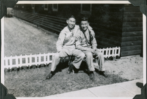 Two men sitting on low bench outside camp building.  Joe Iwataki on left (ddr-ajah-2-477)