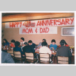 11 people sitting at a table under anniversary banner (ddr-densho-477-579)