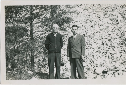 Masahide Yamashita standing in front of an oyster shell pile (ddr-densho-296-8)