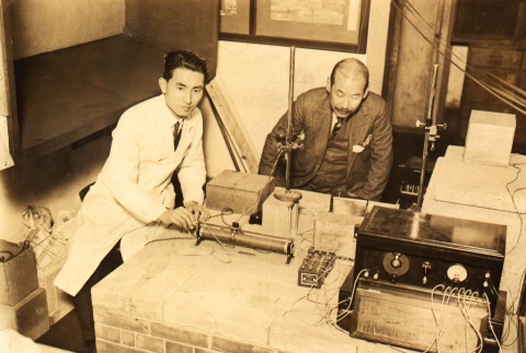 Two men examining a radio [?] (ddr-njpa-4-244)