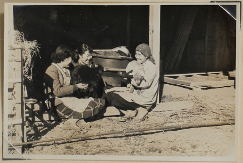Three women smile while holding goats (ddr-densho-433-723)