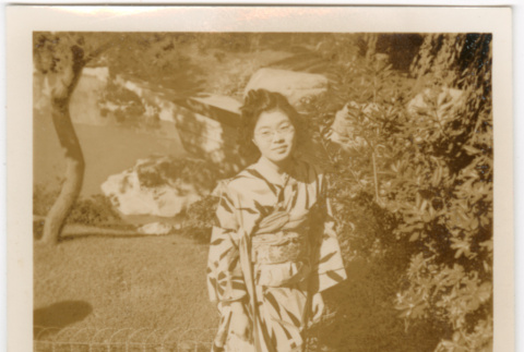 Tomoye (Nozawa) Takahashi in kimono standing in garden (ddr-densho-426-2141)