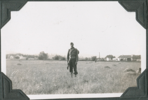 Man with rifle and pack standing in field (ddr-ajah-2-225)