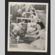 Photograph of women in production line, bucket-like machine in front of them, basket slats piled next to worker (ddr-csujad-55-2612)