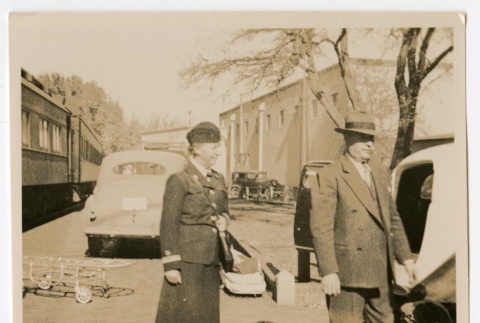 Henrietta Schoen with a man in front of ambulances and a train (ddr-densho-223-8)