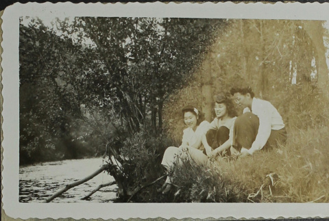 Three women sitting on the banks of a river (ddr-densho-328-556)