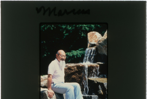 Kaneji Domoto sitting near a waterfall at the Marcus project (ddr-densho-377-459)