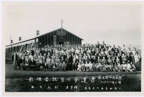 Large group of men and women take a group photo in front of a camp building (ddr-densho-362-53)