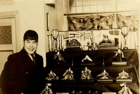 Shiro Otsuji posing next to a display case of dolls (ddr-njpa-4-1701)