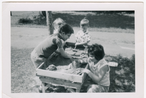 David and Mary Alice playing in a sandbox with two other children (ddr-densho-462-67)