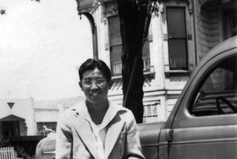 Yoshiharu Inouye sitting on fender of car (ddr-ajah-6-479)