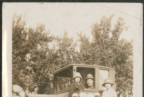 Three people by car with field of flowers (ddr-densho-293-75)