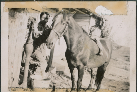 Man standing by horse with boy sitting on horse (ddr-densho-483-577)