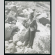 Photograph of a women leaning against a boulder in a rock field near Manzanar (ddr-csujad-47-308)