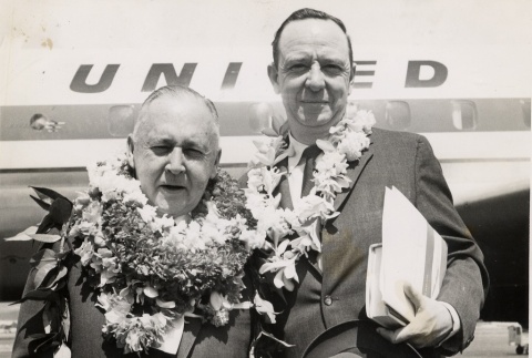 Two men wearing leis posing outside a United airplane (ddr-njpa-2-798)