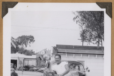 Man leaning on a car bumper (ddr-densho-542-80)