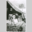 Man in chair in front of tent (ddr-densho-1007-854)