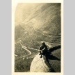Soldier sitting on a wall over a valley (ddr-densho-22-315)