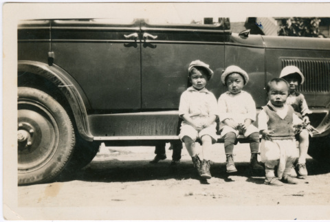 Four children sitting on running board of car (ddr-densho-458-106)