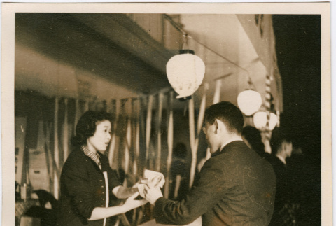 Woman handing package to man across counter (ddr-densho-426-1873)