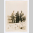 Three men in suits standing behind a low wall (ddr-densho-223-39)