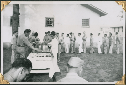 Men lined up by table of food and beer (ddr-densho-434-370)