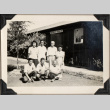 Seven people outside barrack building with sign, Department of Agriculture (ddr-densho-587-18)