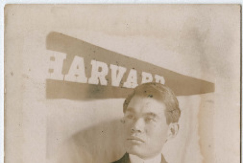 Photo of man in front of Harvard pennant (ddr-densho-355-119)