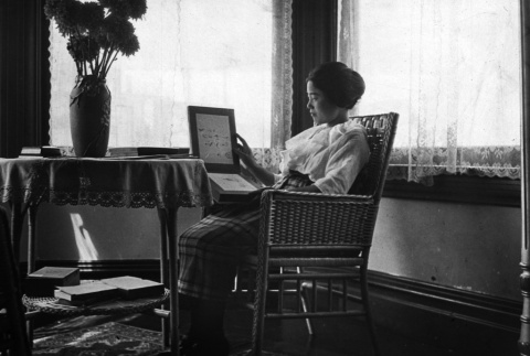 Woman seated by window holding photo album (ddr-ajah-6-560)
