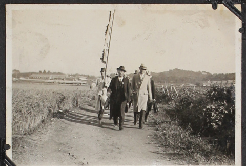 Men walking carrying banner (ddr-densho-326-159)