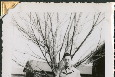 Man standing by tree holding books (ddr-densho-434-323)