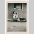 Woman holding toddler girl sitting outside barracks (ddr-densho-329-1276)