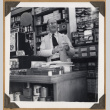 Man behind counter at The Owl Drug Co. (ddr-densho-542-101)