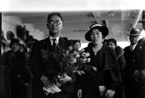 Man holding flowers and woman on board ship (ddr-densho-426-2009)