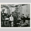 Young woman and man in uniform eating in front of Christmas tree (ddr-densho-122-732)