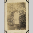 Woman standing by flowers holding tennis racket (ddr-densho-423-499)