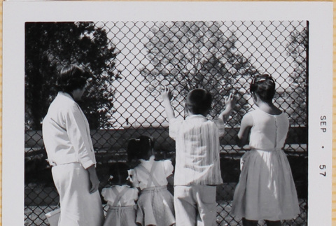 Yoshiko, William, Susan and Leslie Shiomi with unidentified girl standing by fence (ddr-densho-522-416)