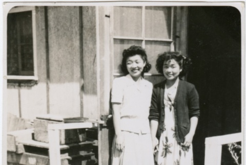 Two girls standing in front of barracks (ddr-densho-292-1)