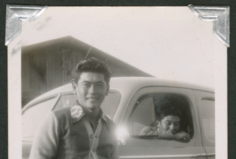 Man leaning on car with someone inside (ddr-densho-550-143)