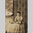 Nisei child sitting on a table (ddr-densho-259-154)