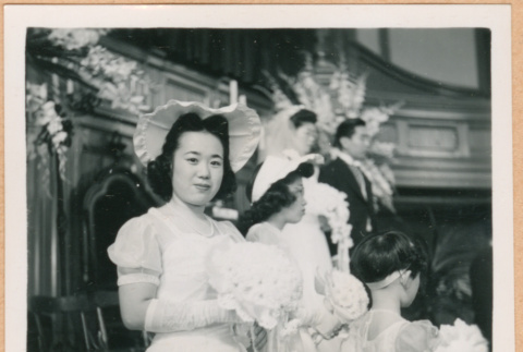 Helen Takahashi looking at camera, wedding party in background (ddr-densho-410-483)