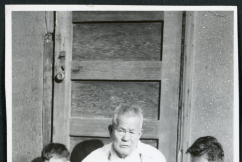 Photograph of Grandpa Tayama surrounded by four children in front of a door in Cow Creek Camp in Death Valley (ddr-csujad-47-131)
