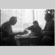 Loni Ding, Barry Saiki and Harry Fukuhara looking through clippings (ddr-densho-1007-1168)