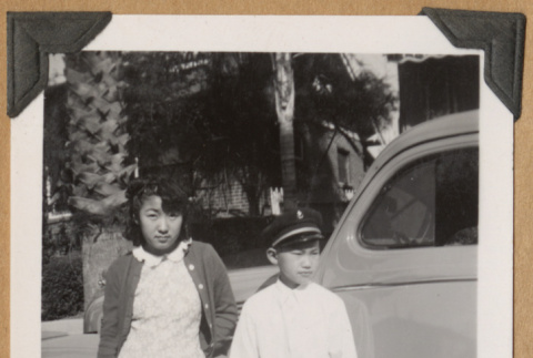 Two children pose by a car (ddr-densho-542-206)