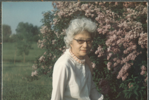 Agnes Sakura sitting on lawn by flowers (ddr-densho-523-660)