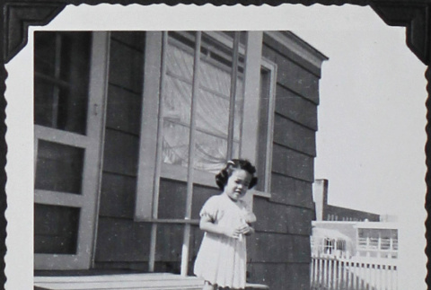 A girl standing on a front porch (ddr-densho-300-513)
