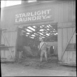 Man working on demolition of building with Starlight Laundry sign over door (ddr-densho-426-2161)