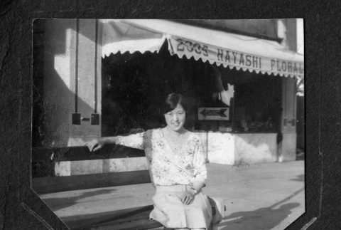 Chiyoko Kono sitting on bench in front of florist shop (ddr-ajah-6-269)